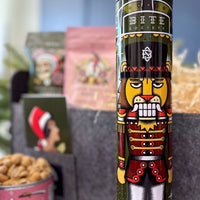 Decorative canister with nutcracker design and 'Bite Society' branding, surrounded by blurred holiday-themed items.