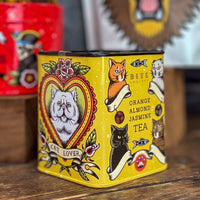 Yellow tea canister with cat-themed design on a wooden surface