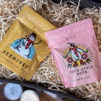 Two colorful packages of 'Beehives' and 'Sour Apple Dots' on a textured surface.