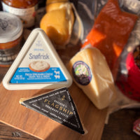 Three types of cheese on a wooden surface with a blurred background
