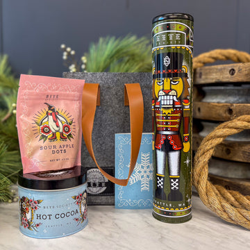 Decorative hot cocoa container, pink bag with sour apple dots, and nutcracker tin with ginger snap cookies