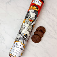 Tin of Zesty Chocolate Cookies with decorative label on a white surface with cookies.