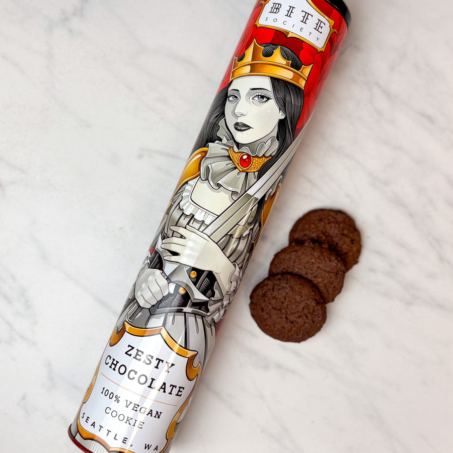 Tin of Zesty Chocolate Cookies with decorative label on a white surface with cookies.