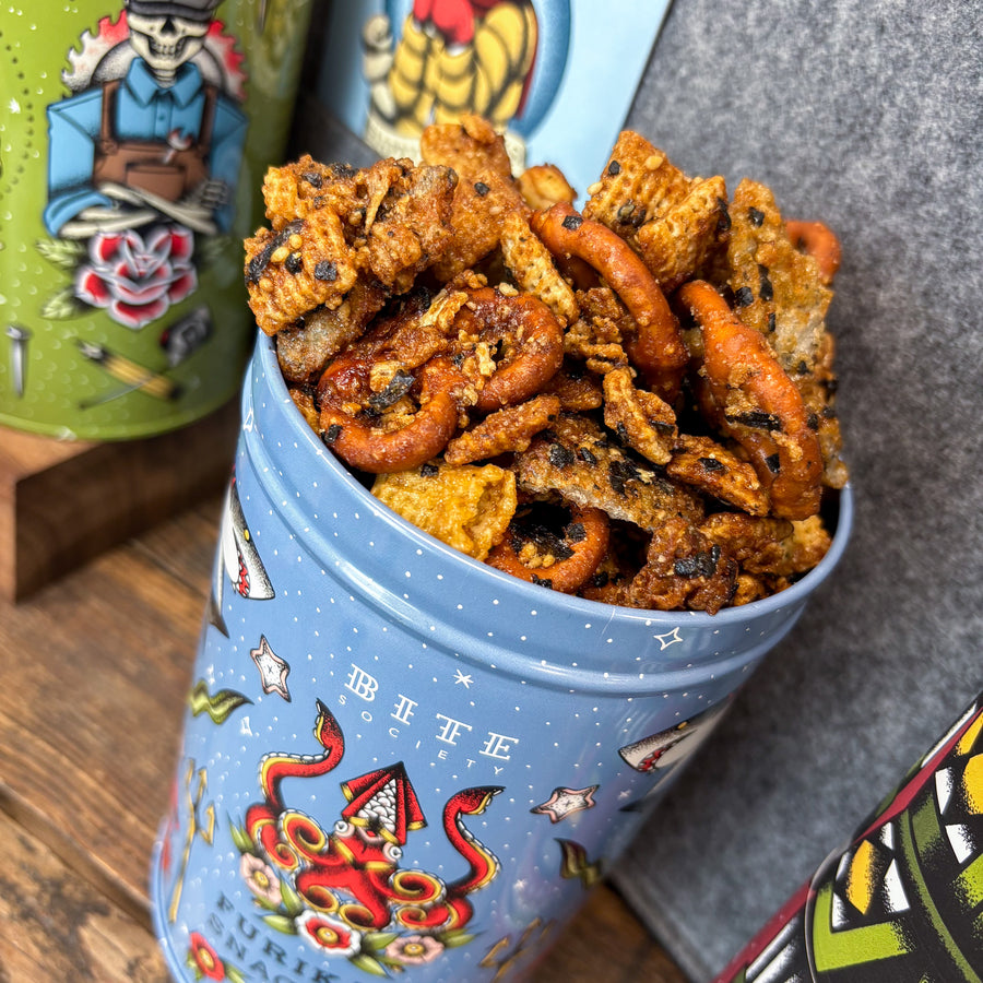 Furikake Snack mix in a blue decorative tin with colorful labels on a wooden surface