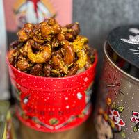 Red tin filled with spiced nuts next to a tin of potato chips