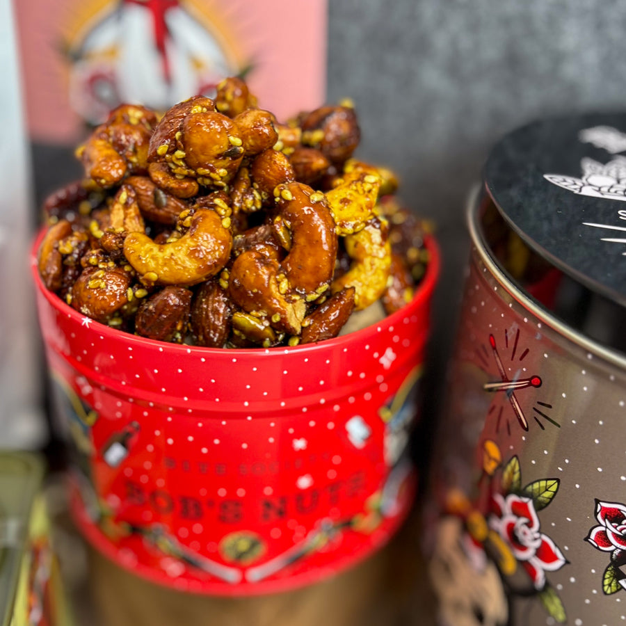 Red tin filled with spiced nuts next to a tin of potato chips
