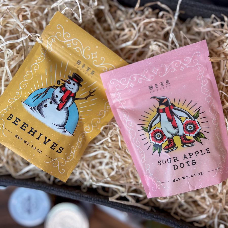 Two colorful packages of 'Beehives' and 'Sour Apple Dots' on a textured surface.