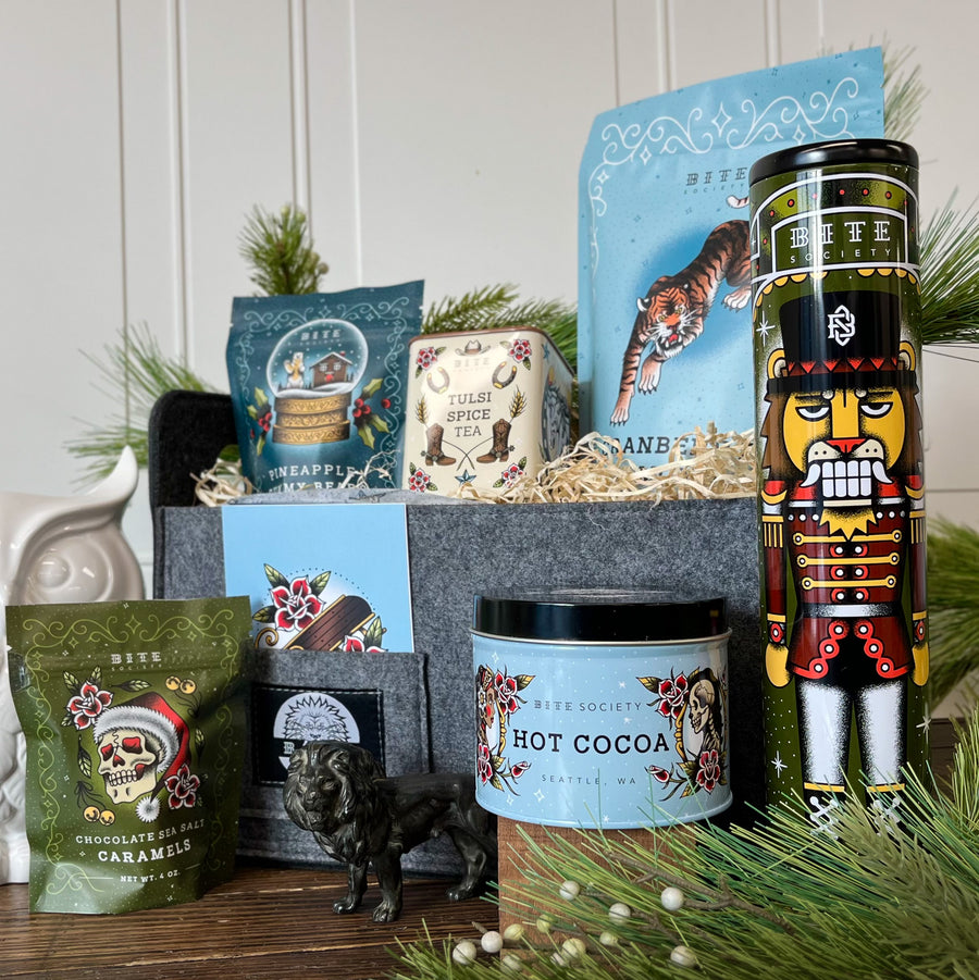 Snow Day Holiday Gift Basket. Collection of holiday-themed products including candles, tea and cocoa tins, and ginger snap cookie tin.